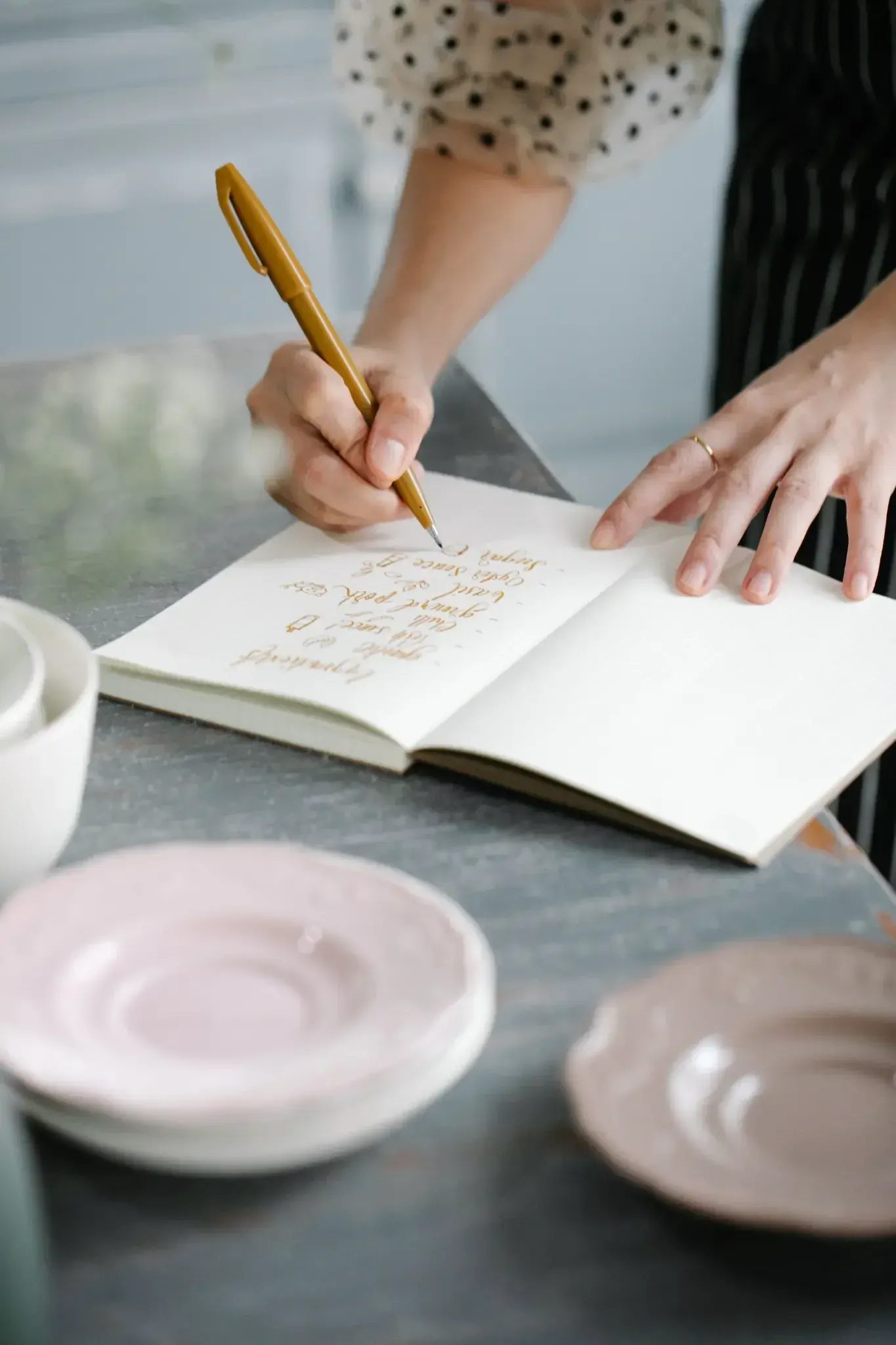 A woman writing by hand beside a cooling cup, saying it to the page instead.