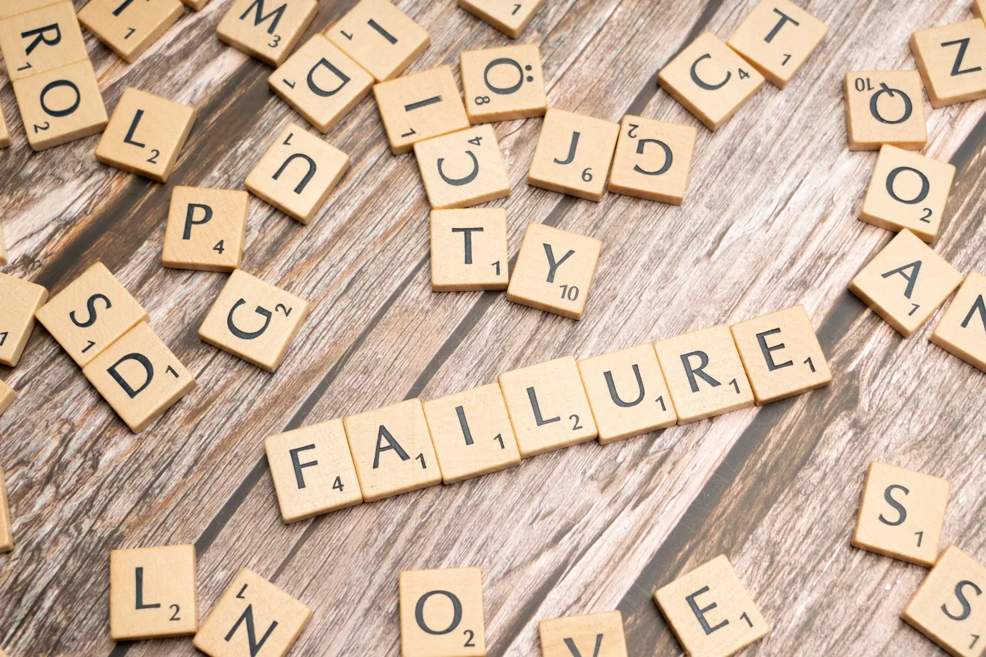 FAILURE spelled out in wooden tiles, a word that can be lifted and laid down again.