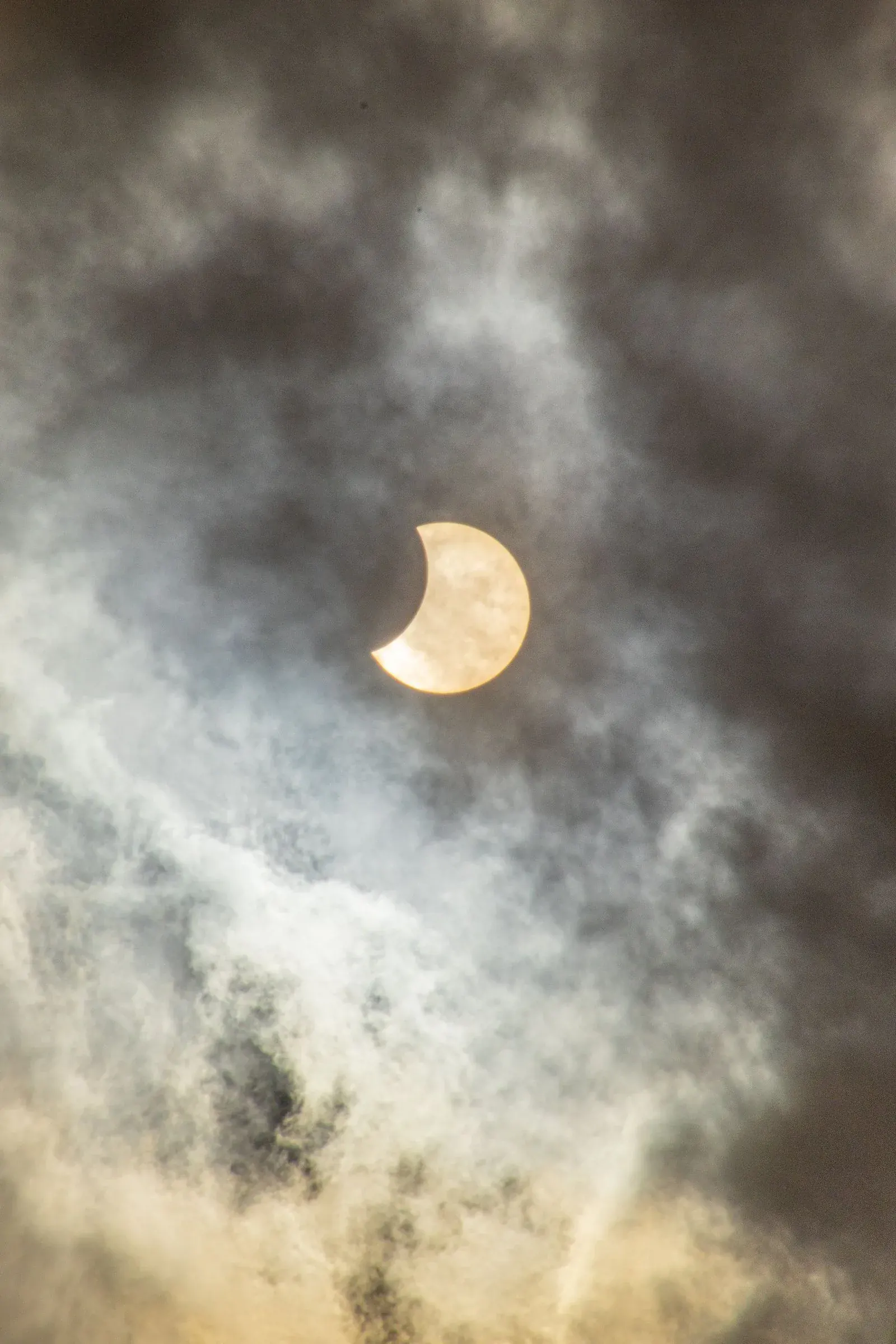 A crescent of sun behind heavy cloud, light stepping aside for a moment.