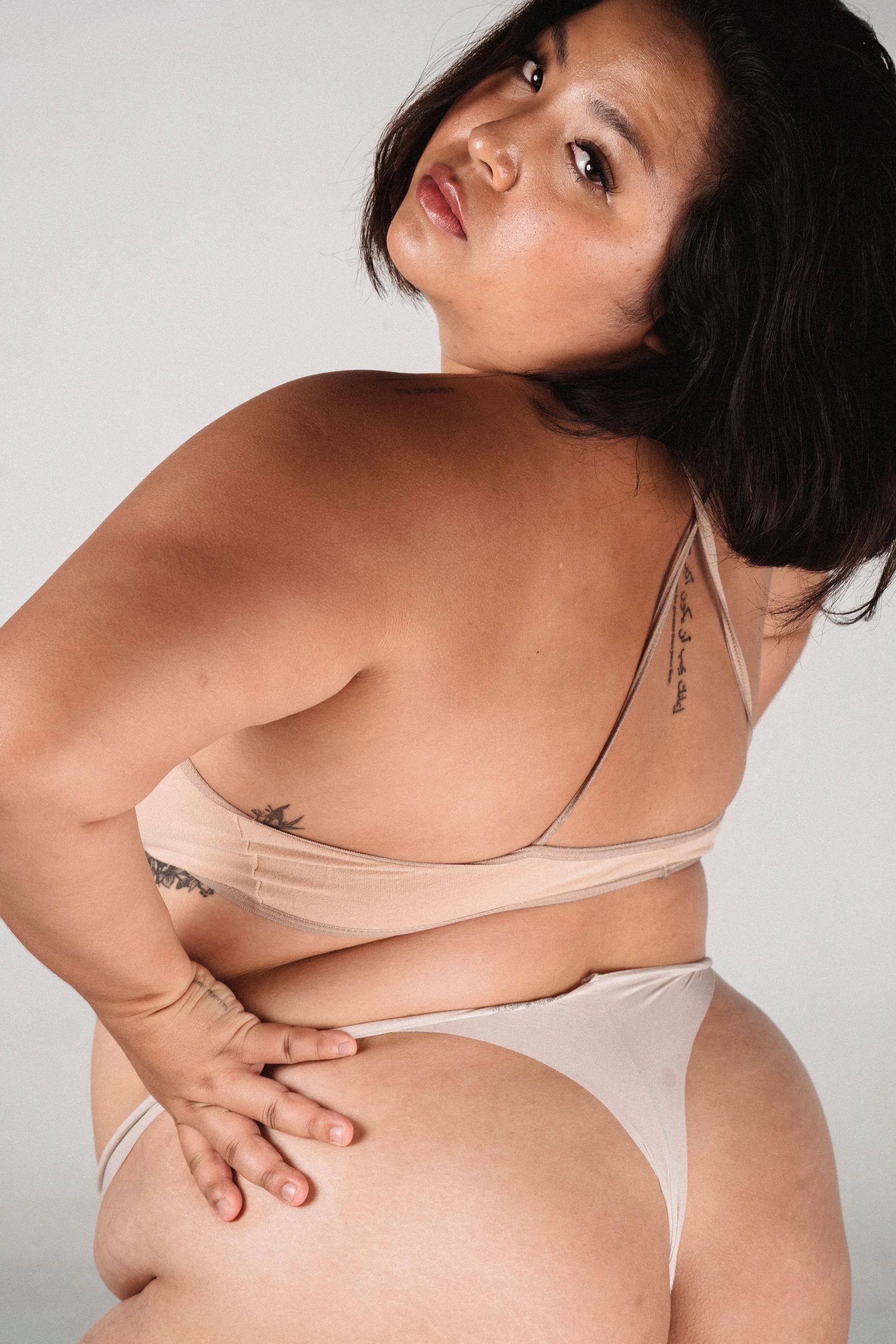 A woman looking back over her shoulder, at ease in the body she actually has.