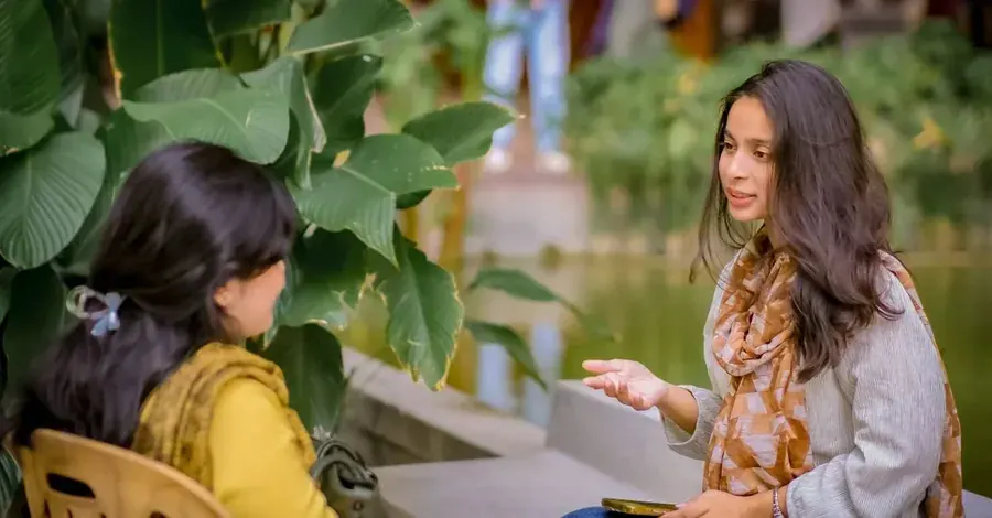 Two women in real conversation among the leaves, company turned into connection.