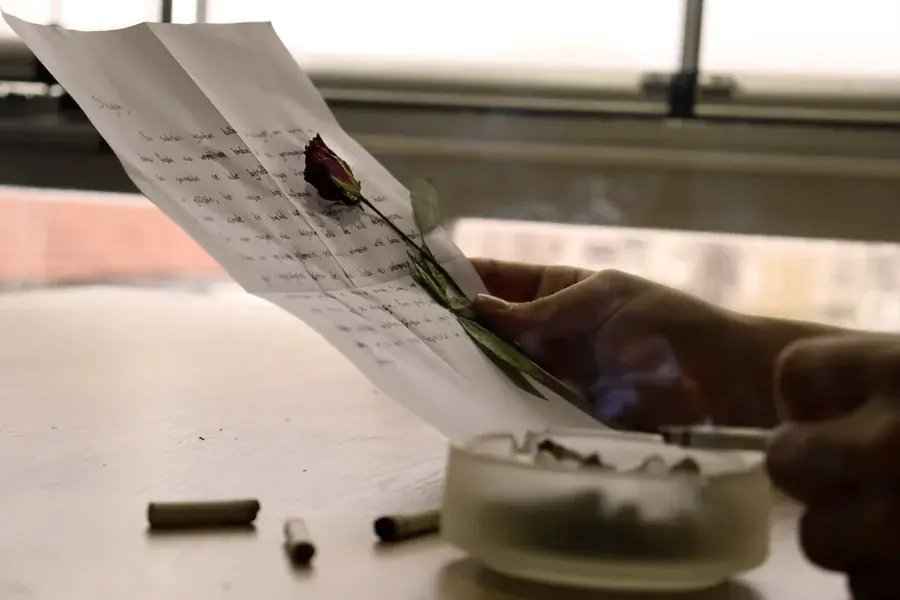 Hands holding a letter and a dried rose, words kept for the woman still becoming.
