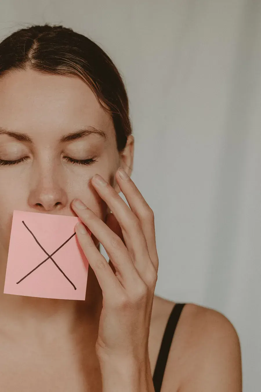 A note with a cross on it held over her mouth, the sentence she stopped saying to herself.