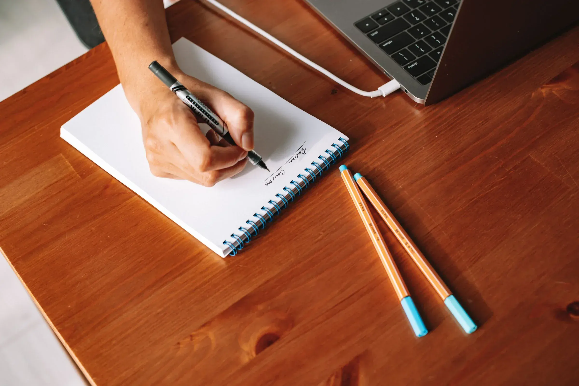 A hand writing the question out by hand first, before any tool tries to answer it.