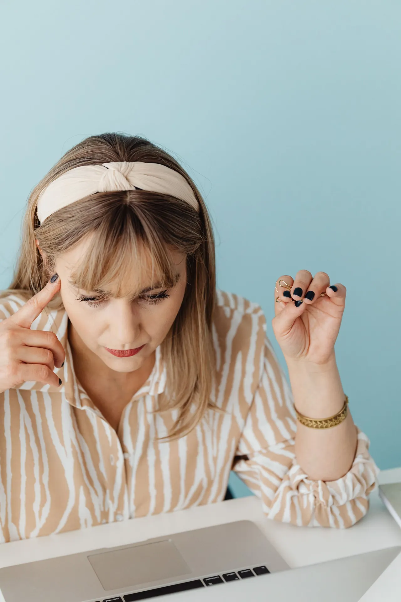 A woman with a finger at her temple, losing to the tool that promised to make it simpler.