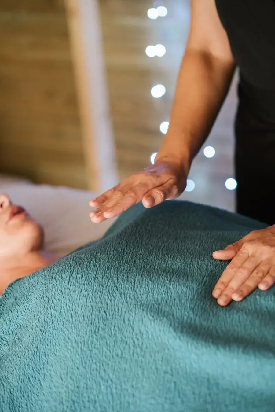 A practitioner's hands held above a resting body, stillness doing its own work.