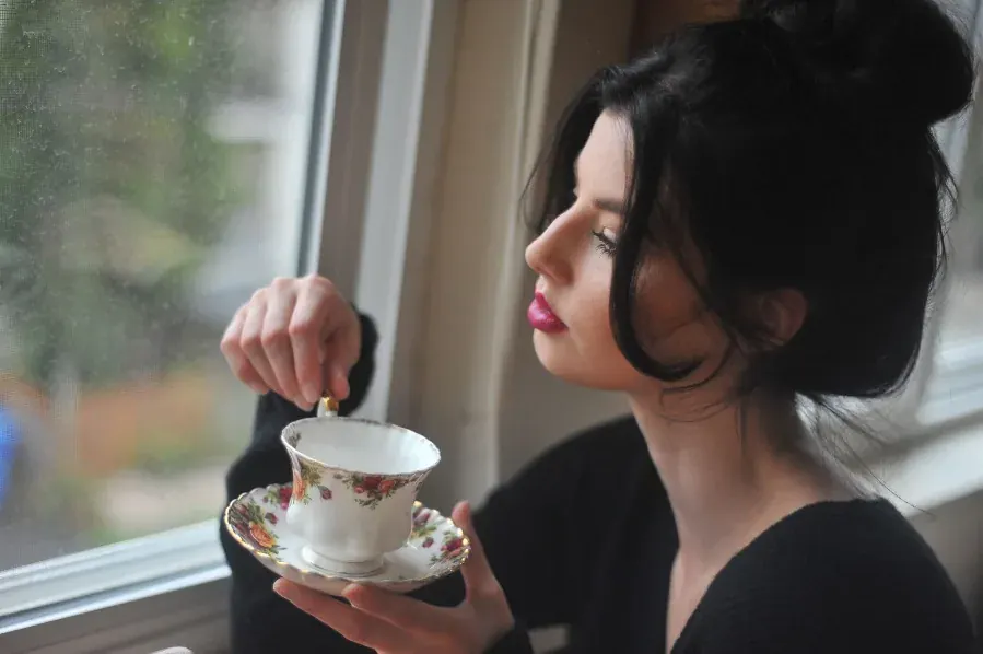 A woman with her tea at the window, no apology for the years in it.
