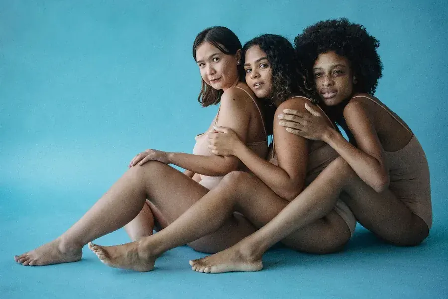Three women leaning into each other, bodies at rest rather than under review.