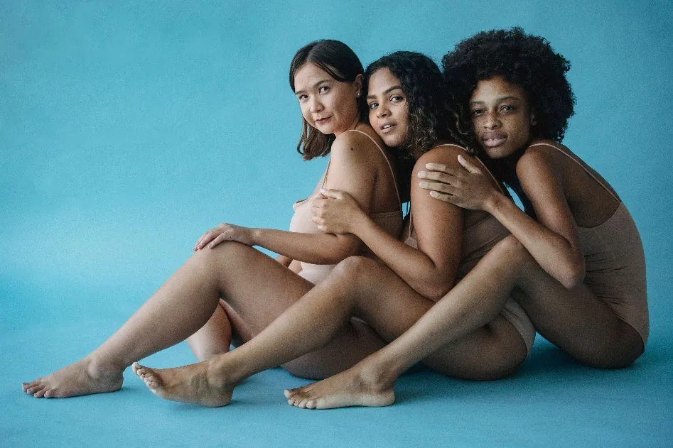 Three women leaning into each other, bodies at rest rather than under review.