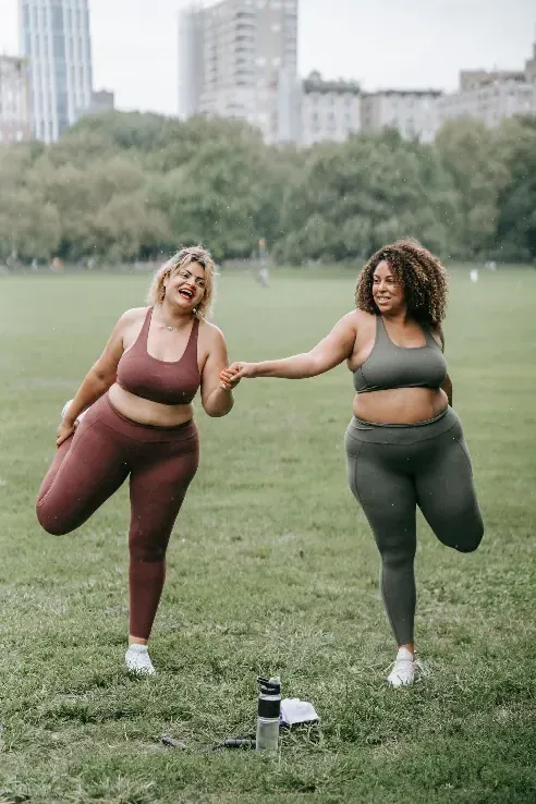 Two women steadying each other mid-stretch, more than fine and enjoying it.