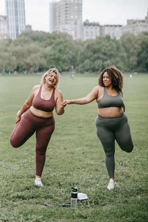 Two women steadying each other mid-stretch, more than fine and enjoying it.